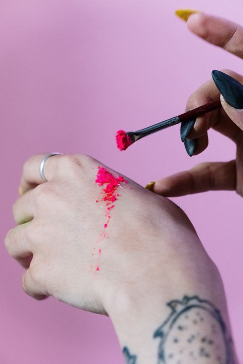 Free A tattooed hand applying bright pink makeup on a skin with a brush against a pink background. Stock Photo