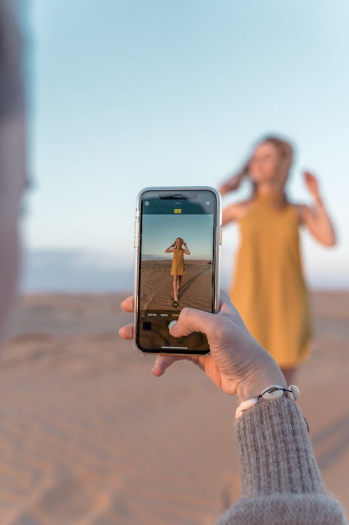 Free 
A Person Taking a Picture of a Woman with a Smartphone Stock Photo