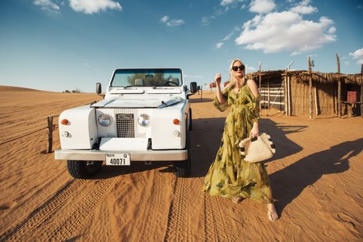 Woman posing with a vintage Land Rover in the desert. Stylish and retro vibe.