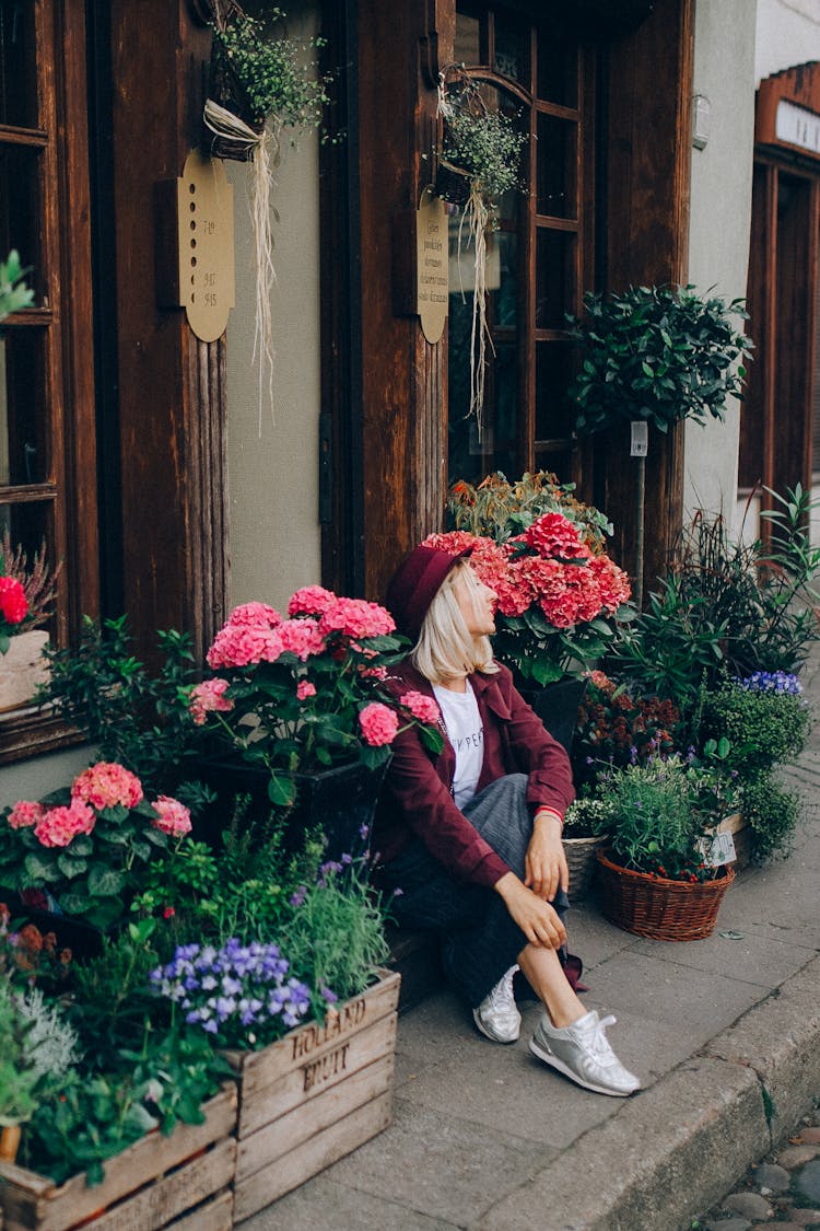 Woman Sitting Near Potted Flowers