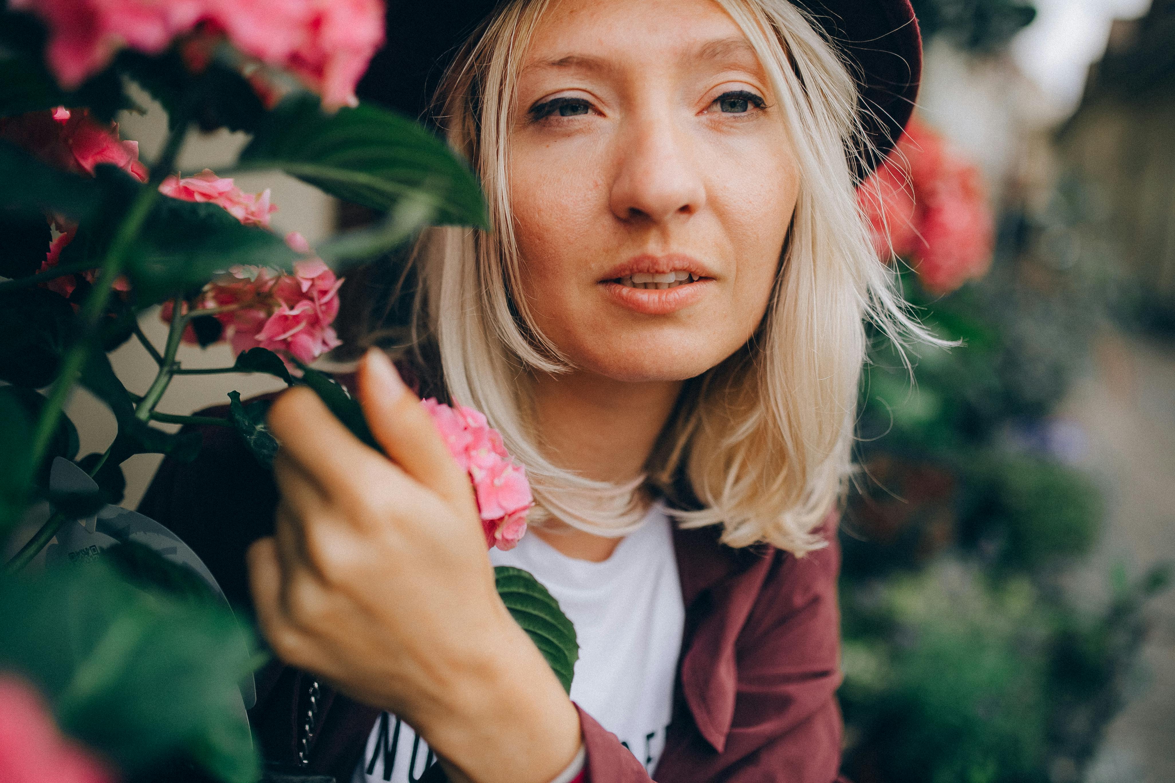 woman with blond hair holding a flowering plant