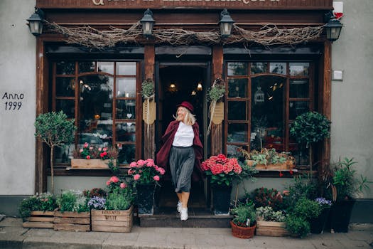 Stylish woman in red hat outside a flower shop surrounded by vibrant autumn flowers.
