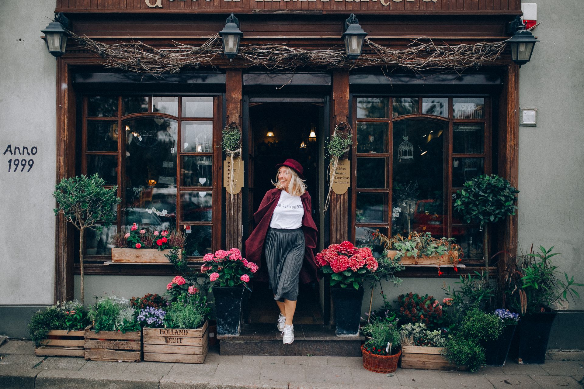 Woman in Red Coat and Hat Standing on a Doorway of a Shop