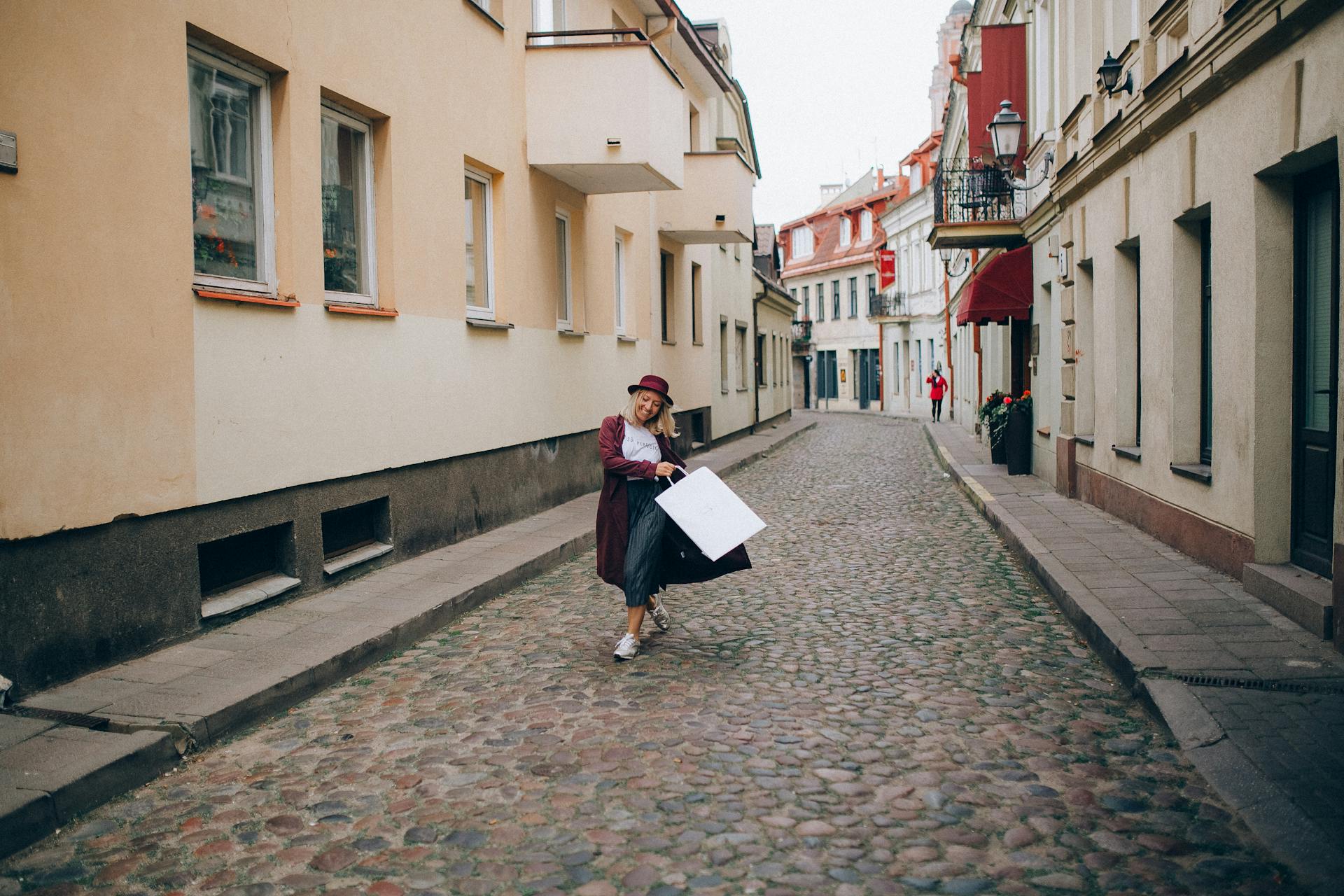 Woman Wearing a Red Hat and Coat Holding a Paper Bag