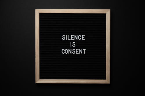 Free From above blackboard with written phrase SILENCE IS CONSENT on center on black background Stock Photo