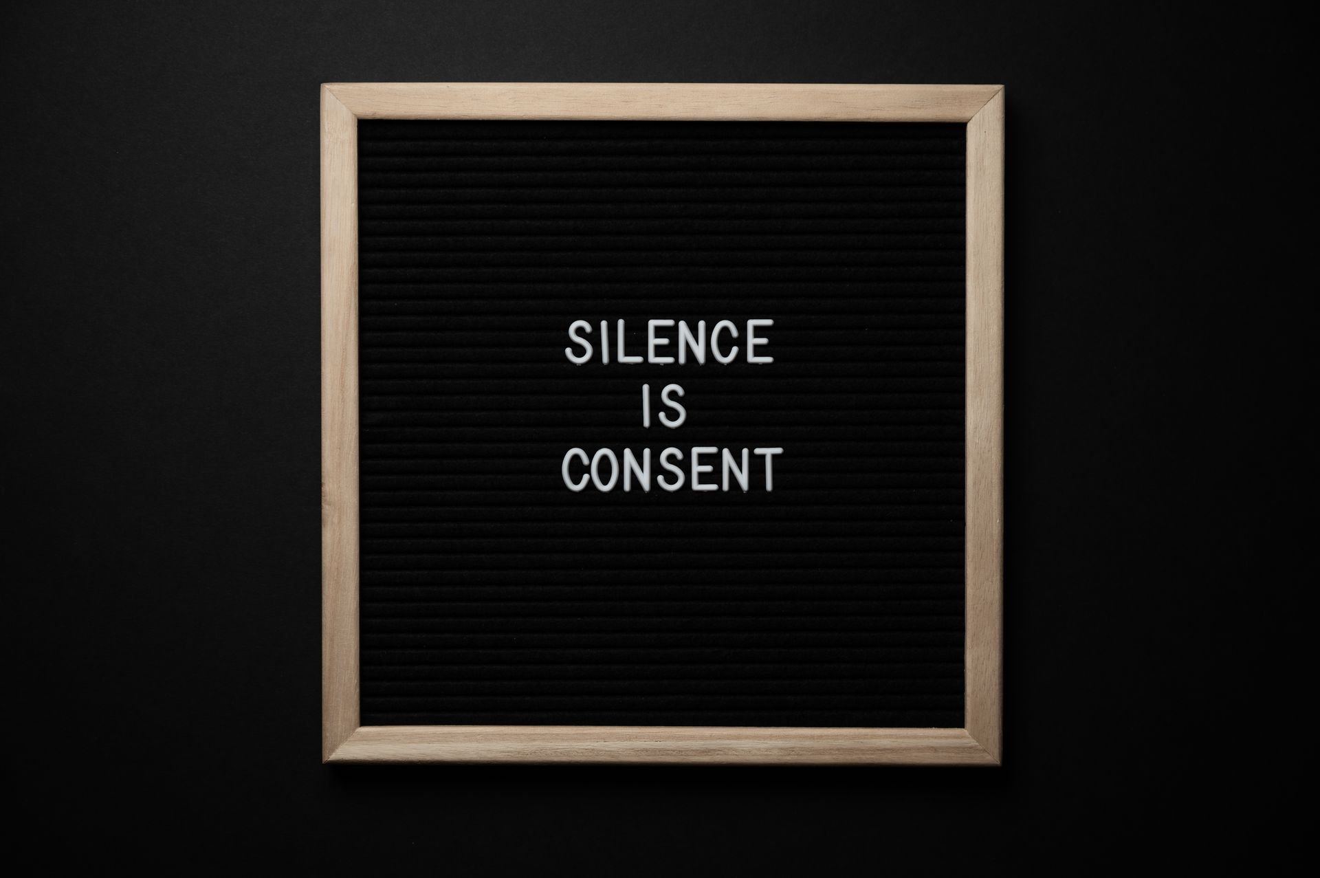 From above blackboard with written phrase SILENCE IS CONSENT on center on black background