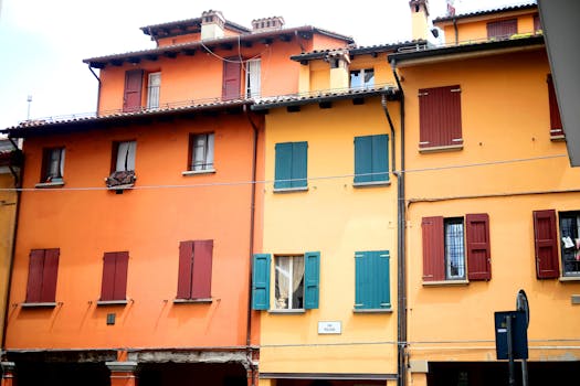 Vibrant orange and yellow buildings line a street in Bologna, showcasing classic Italian architecture.