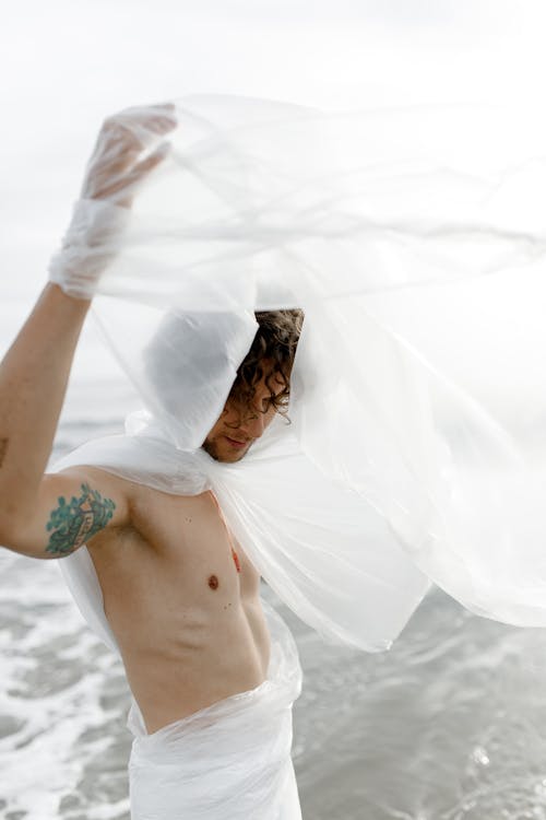 Free Shirtless Man With Arm Tattoo Wrapped in Plastic Sheet Stock Photo