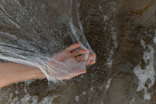 Free Person's Hand in Plastic Sheet on Water Stock Photo