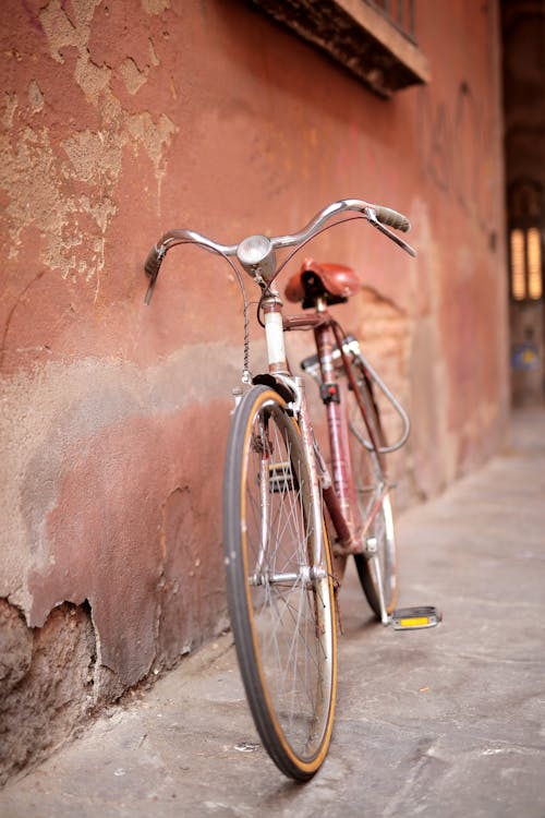A Bicycle Leaning on Brown Wall