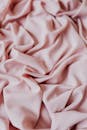 柔软粉色面料特写，带有折痕和褶皱，是理想的纹理背景