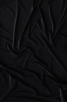 A detailed shot of a crumpled black fabric, showcasing its smooth and wrinkled texture in a monochromatic tone.