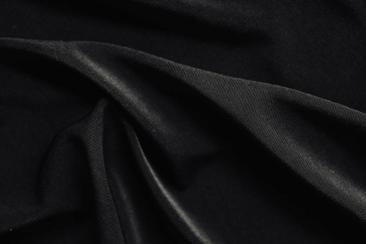 Black fabric folds revealed by directional light and shadow