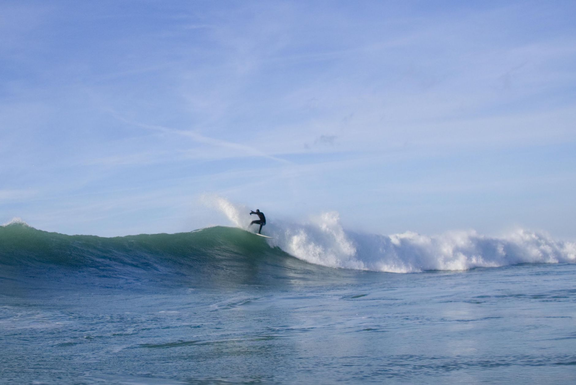 A surfer catches a wave on a sunny day, showcasing the thrill of surfing.