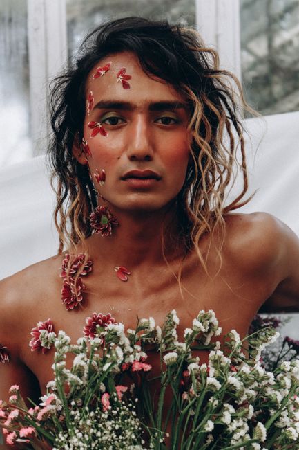 Creative portrait capturing a person with floral adornments and natural makeup, conveying artistic expression.