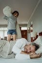 A Girl Holding a Pillow Standing on Bed