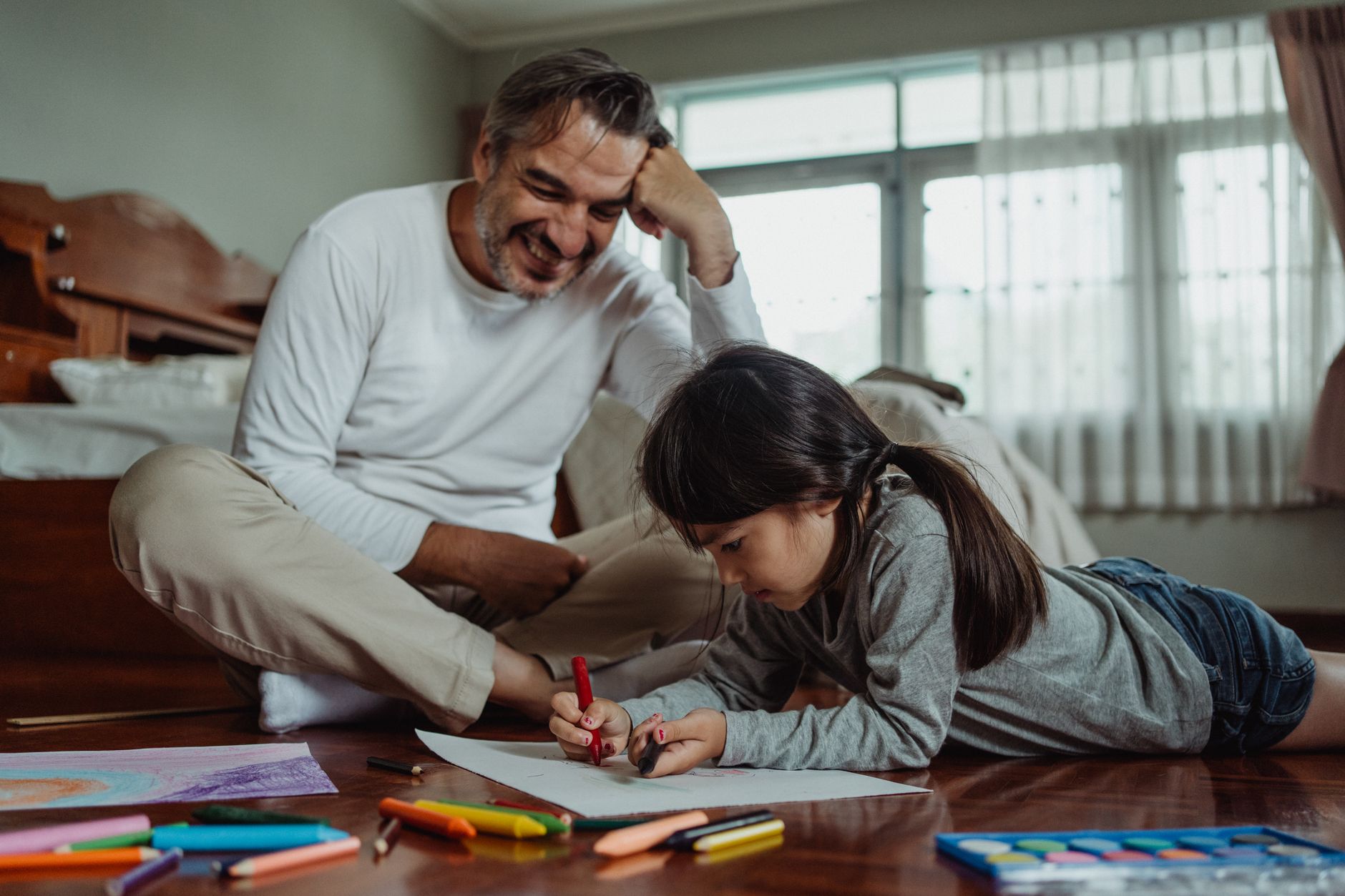 Father and daughter enjoying a creative coloring session together indoors.