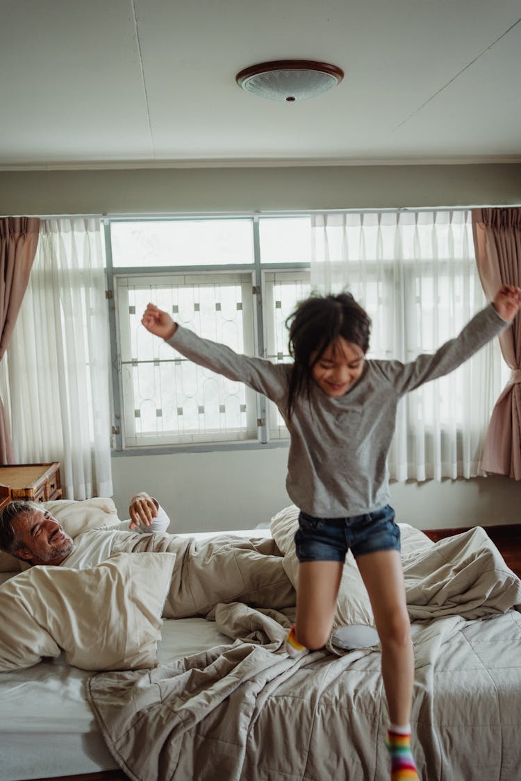 A Girl In Gray Long Sleeves Jumping Out Of Bed