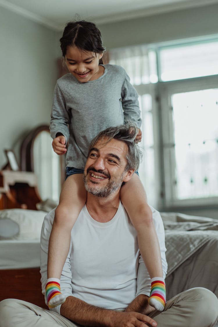 A Girl Sitting On A Man's Shoulders 