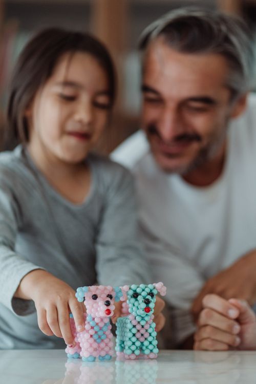 Free A joyful moment as a father and daughter bond over colorful bead toys indoors. Stock Photo