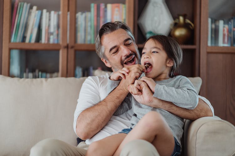 Father And Daughter Sharing Chocolate In A Stick