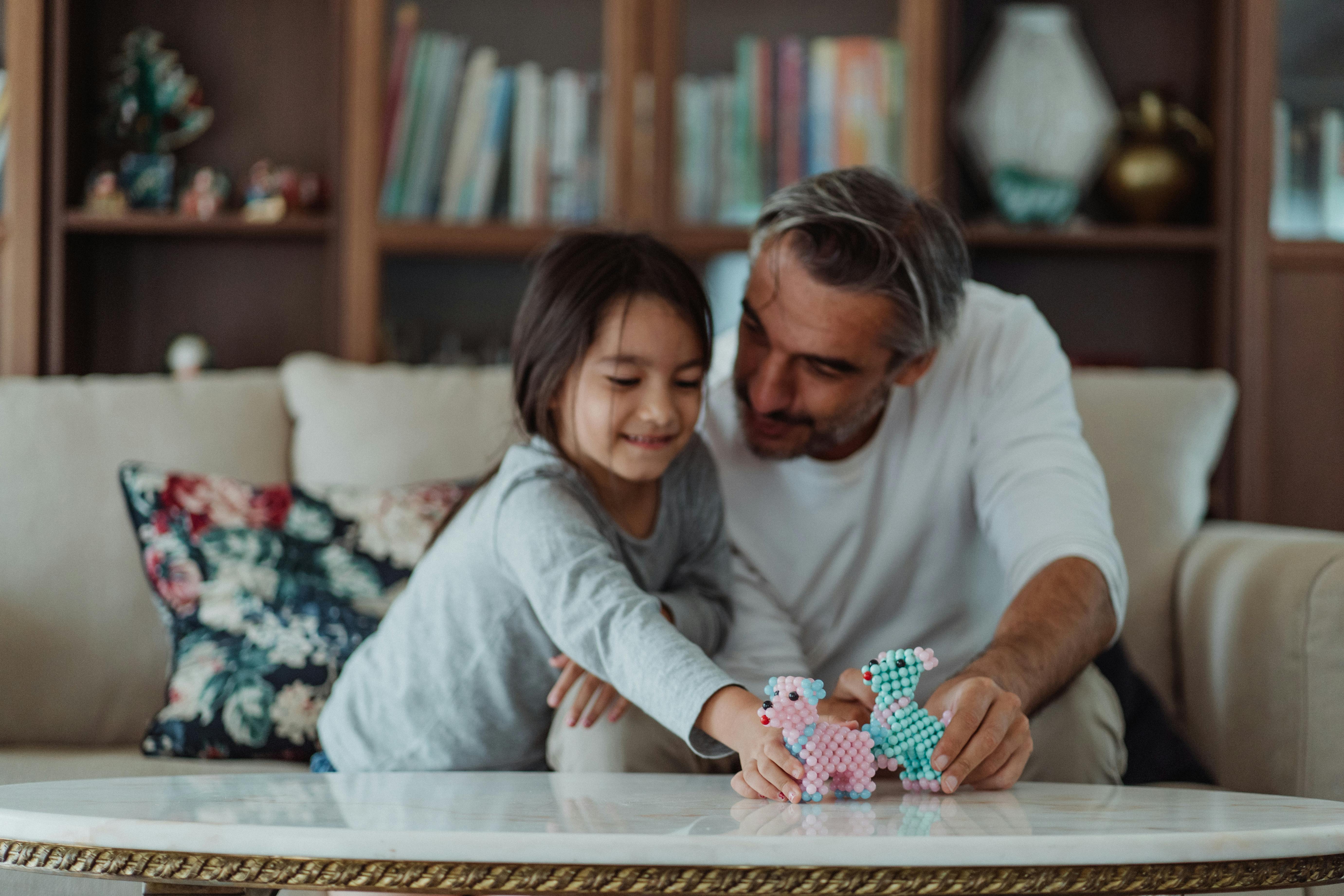 father and daughter sitting in the couch while playing