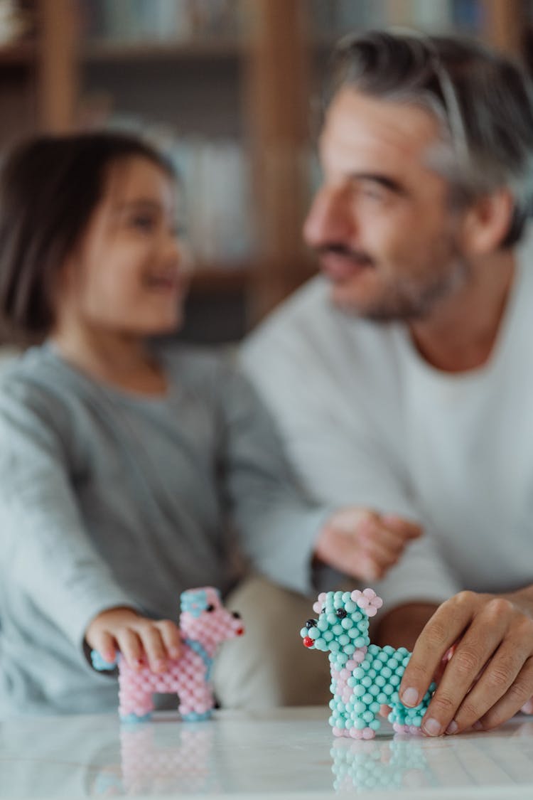 A Man And A Girl Holding Dog Toys Made Of Beads 