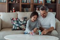 Father and Daughter Playing with Toy Ponies