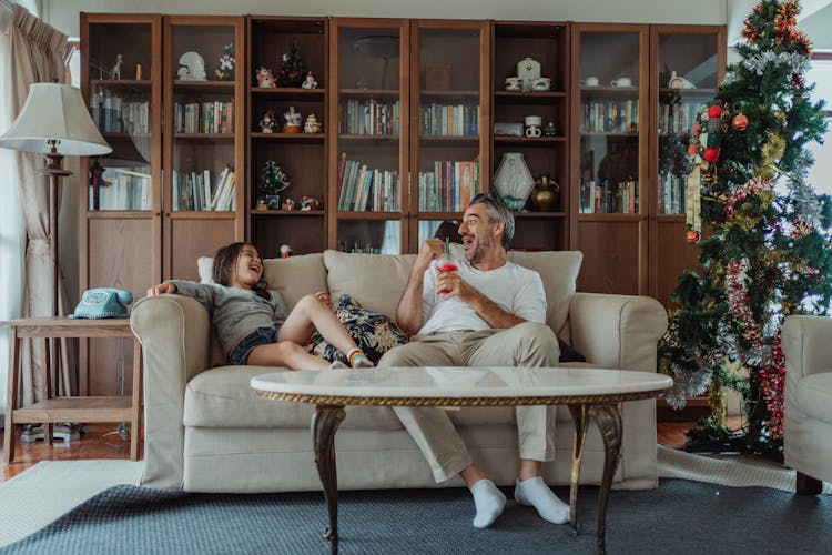 A Man And A Girl Laughing While Sitting On The Couch