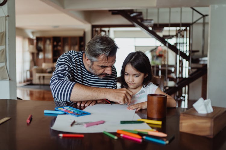 Father And Daughter Drawing And Painting Together At Home