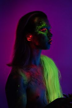 在黑光下，一个人画着鲜艳的霓虹妆，创造出荧光效果
