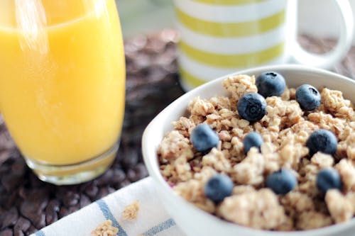 Bowl of Oatmeal With Berries Beside Glass of Juice
