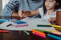 一位年轻女孩在室内用水彩和彩色铅笔进行艺术创作