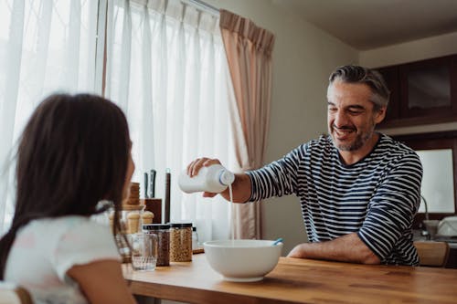 Free Father Pouring Milk Into Daughters Cereal Stock Photo