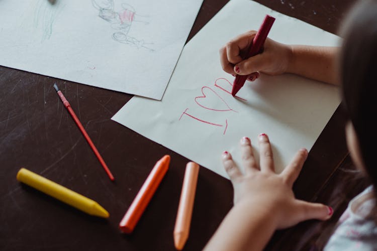 Girl Writing On Paper With A Crayon