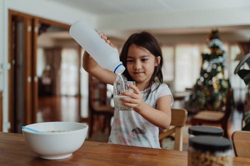 Free Little Girl Pouring Herself Glass of Milk Stock Photo