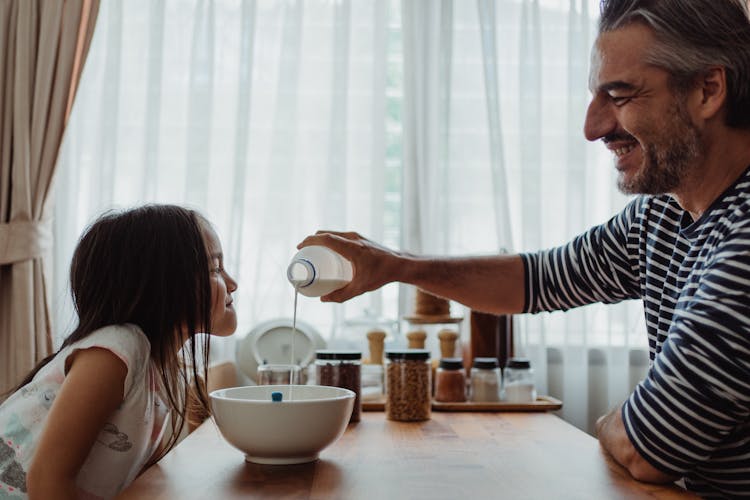 Father Pouring Milk Into Daughters Bowl