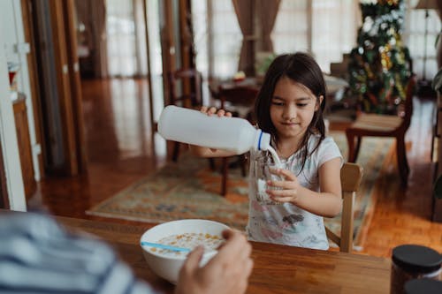 Free Girl Pouring Milk into Glass Stock Photo