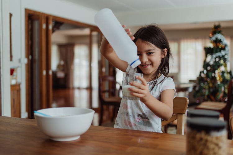 Little Girl Pouring Herself Glass Of Milk