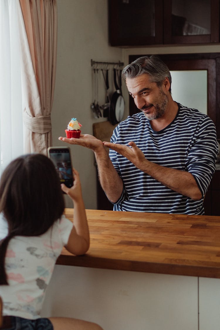 A Girl Taking A Picture Of A Cupcake