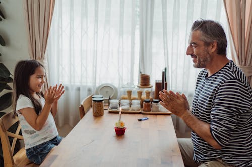 Father and Daughter at Kitchen Table with a Cupcake Clapping Hands 