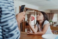 Girl in White and Blue Stripe Shirt Holding Iphone