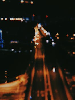Blurred nighttime view of a road and city lights in Singapore, capturing urban ambiance.