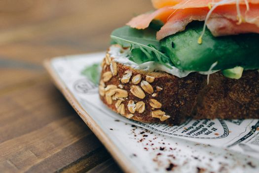 Close-up view of a nutritious sandwich with seeds, cucumber, and spinach on whole grain bread.