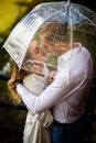 这对恩爱的夫妇在雨中撑着透明伞，共享亲密时刻