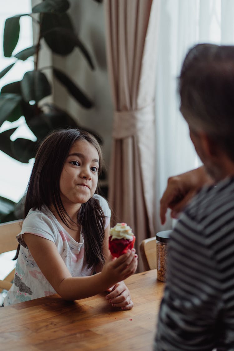 A Little Girl Holding A Cupcake