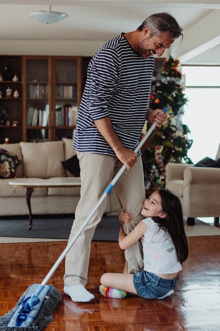 Father And Daughter Mopping And Playing At Home