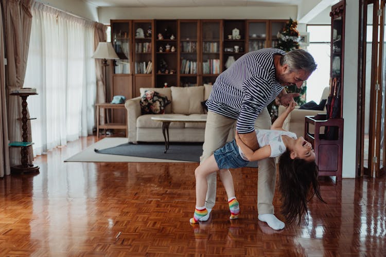 Father And Daughter Dancing In The Living Room