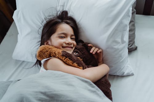 Free Little Smiling Girl with Cuddly Toy in Bed Stock Photo
