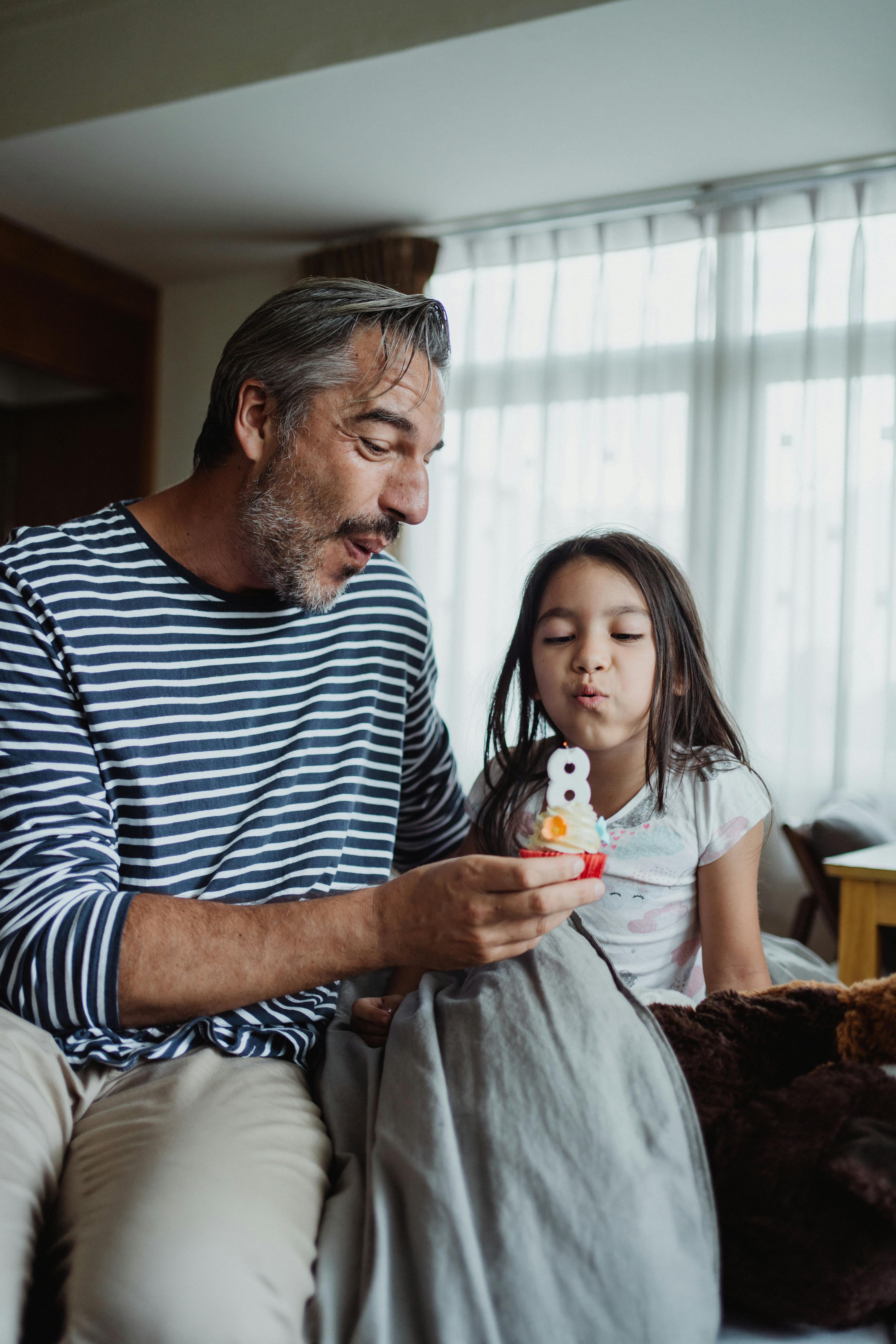 Father and Daughter Blowing Out a Candle on a Birthday Cupcake · Free Stock  Photo